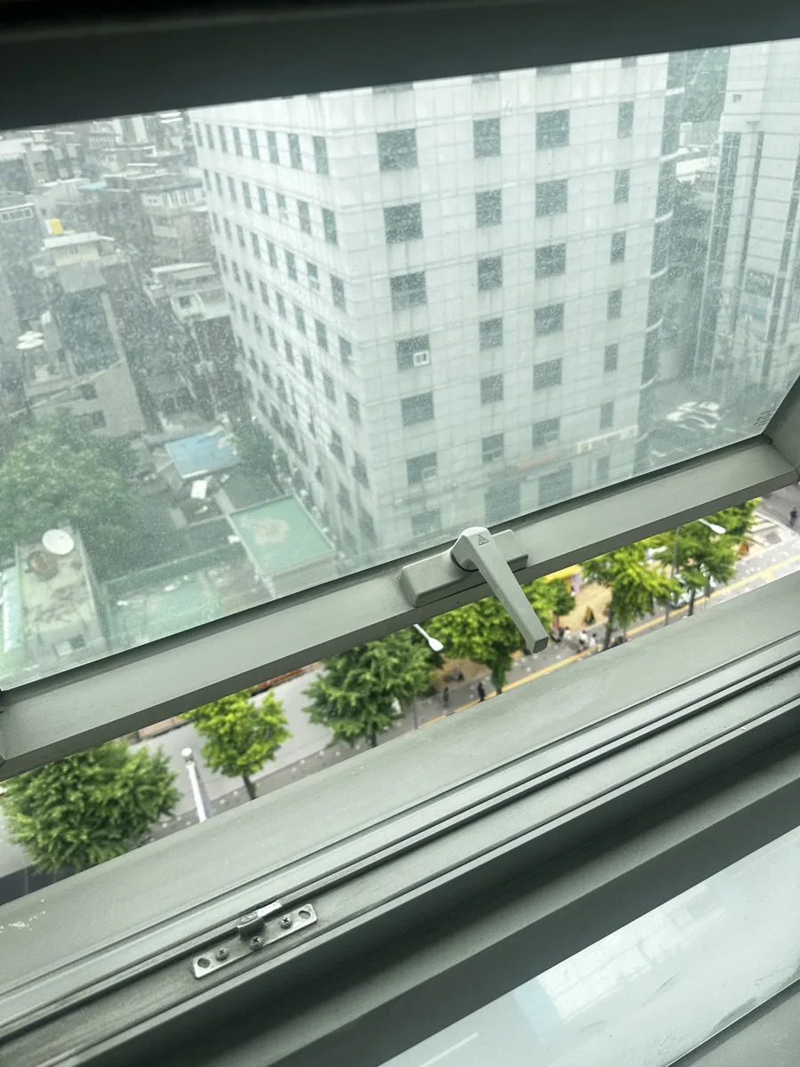 아파트 고층 베란다 창문 틈으로 보이는 도심 전경
