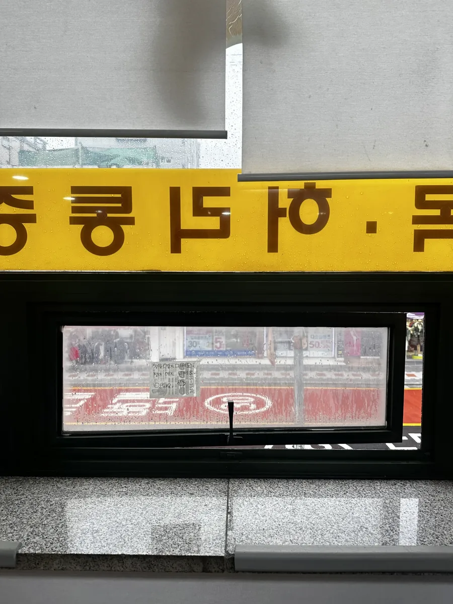 상가 창문에 붙은 안내 스티커와 외부 상권 전경